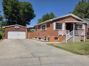 View of front of property featuring driveway, a front yard, brick siding, and an outdoor structure