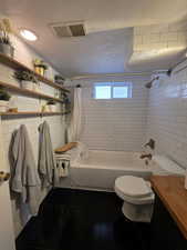 Bathroom featuring tile patterned flooring, shower / tub combo with curtain, vanity, and a textured ceiling