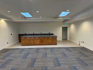 Kitchen with a skylight, light carpet, recessed lighting, and brown cabinetry