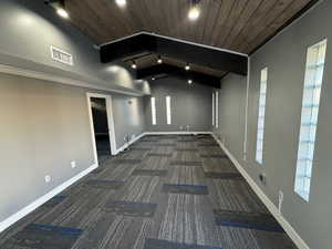 Carpeted spare room featuring a wooden ceiling with exposed beams and track lighting
