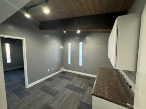 Spare room featuring dark carpet, a wood ceiling with exposed beams, and rail lighting