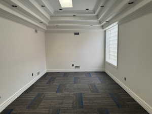 Empty room featuring a tray ceiling, carpet floors, and ornamental molding