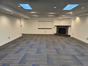 Unfurnished living room featuring a skylight, carpet floors, a high end fireplace, and recessed lighting