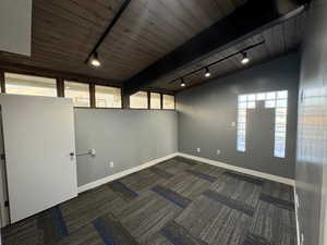 Unfurnished room with rail lighting, carpet floors, wood ceiling, plenty of natural light, and lofted ceiling