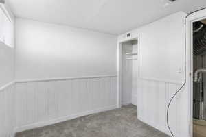 Unfurnished bedroom featuring a wainscoted wall, a closet, carpet, and a decorative wall