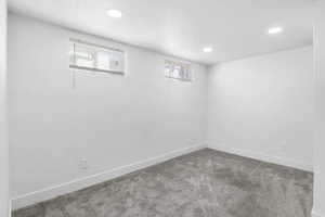 Basement with carpet floors, a textured ceiling, and recessed lighting