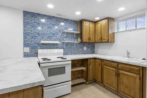 Kitchen featuring open shelves, electric stove, tasteful backsplash, brown cabinets, and light countertops