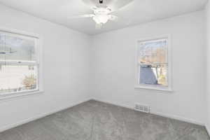Spare room featuring carpet and ceiling fan
