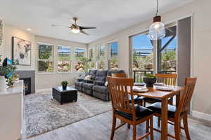 Dining room featuring light wood-style floors, ceiling fan, a tiled fireplace, and recessed lighting