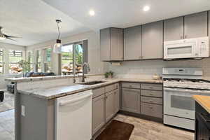 Kitchen with white appliances, gray cabinets, a peninsula, and recessed lighting