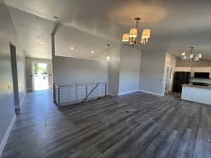 Unfurnished living room featuring a chandelier, dark wood-style flooring, a textured ceiling, and recessed lighting