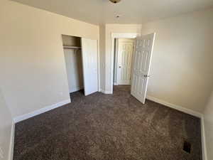 Unfurnished bedroom with dark carpet and a closet