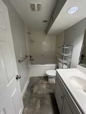 Bathroom featuring vanity, stone finish flooring, and  shower combination