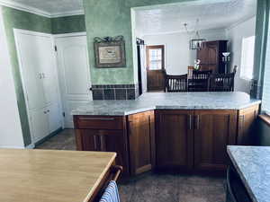 Kitchen featuring a textured ceiling, light countertops, and crown molding