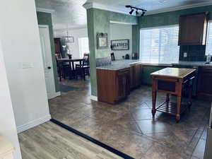 Kitchen with crown molding, a textured ceiling, backsplash, and light countertops