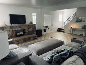 Living area featuring wood finished floors, ornamental molding, and stairs