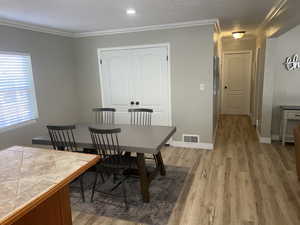 Dining space with light wood-type flooring and crown molding