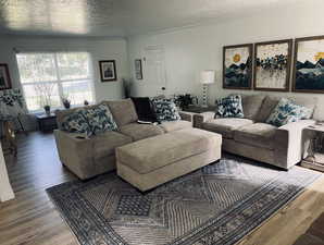Living room featuring wood finished floors, a textured ceiling, and ornamental molding