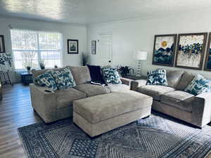 Living area with a textured ceiling, wood finished floors, and crown molding