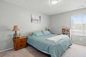 Carpeted bedroom featuring a textured ceiling and baseboards