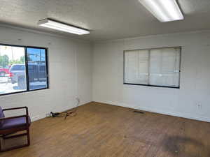 Empty room featuring a textured ceiling, wood finished floors, and concrete block wall