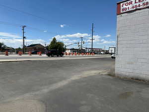 View of asphalt street featuring street lighting and sidewalks