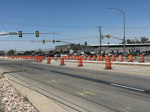 View of asphalt street with traffic lights, sidewalks, street lighting, and curbs