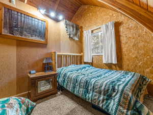 Bedroom with lofted ceiling, wood ceiling, and carpet