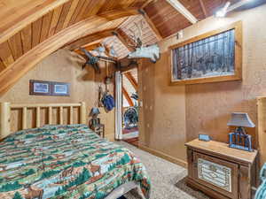 Bedroom featuring wood ceiling, carpet floors, vaulted ceiling, and wood walls