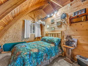 Bedroom featuring wood ceiling, carpet floors, and wood walls