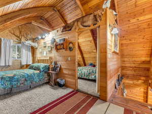 Carpeted bedroom with wood walls and wood ceiling