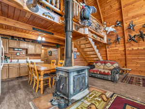 Kitchen featuring a wood stove, wooden walls, a wood ceiling with exposed beams, dark wood-style flooring, and light countertops