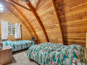 Bedroom with wood ceiling, carpet flooring, and wooden walls