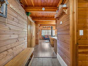 Hall featuring a wooden ceiling with exposed beams and wood walls
