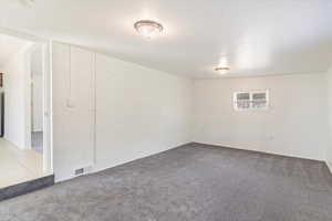 Carpeted empty room featuring brick wall and baseboards