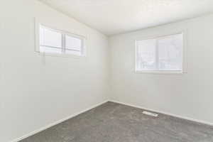 Unfurnished room featuring baseboards and dark carpet