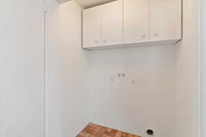 Laundry room featuring cabinet space, electric dryer hookup, brick patterned floors, and washer hookup