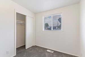 Unfurnished bedroom with dark colored carpet and a closet