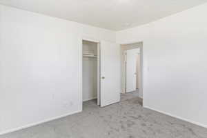 Unfurnished bedroom featuring light colored carpet and a closet