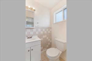 Bathroom featuring vanity, tile patterned flooring, tile walls, and wainscoting