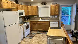 Kitchen with white appliances, light countertops, brown cabinets, stone finish floors, and decorative backsplash