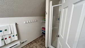 Laundry room featuring baseboard heating, a textured ceiling, and stone finish floors