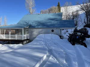 View of snowy exterior featuring a metal roof and a deck, you will need a tracked vehicle in the winter
