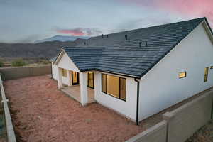 Back of house featuring a mountain view, stucco siding, a fenced backyard, and a patio area