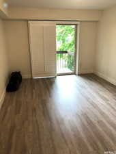 Unfurnished bedroom with access to exterior and dark wood-type flooring