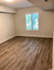 Unfurnished room with baseboards and dark wood-type flooring