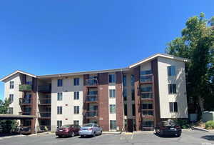 View of apartment building entrance / complex featuring uncovered parking