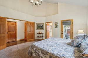 Carpeted bedroom featuring high vaulted ceiling and a chandelier
