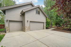 View of side of home featuring stone siding, driveway, and an attached garage