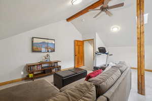 Carpeted living area featuring ceiling fan and baseboards